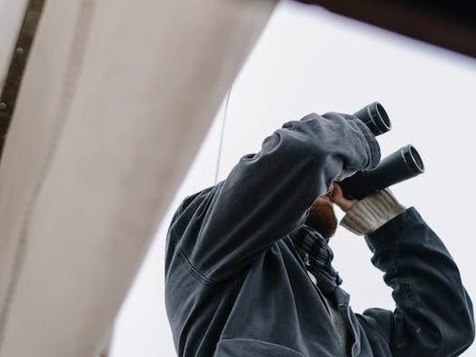 person in gray jacket holding black dslr camera